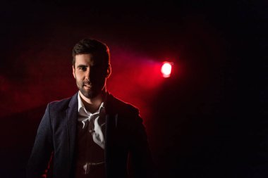 Ayakta duran adamın fotoğrafı ve arka planda pembe ışık..