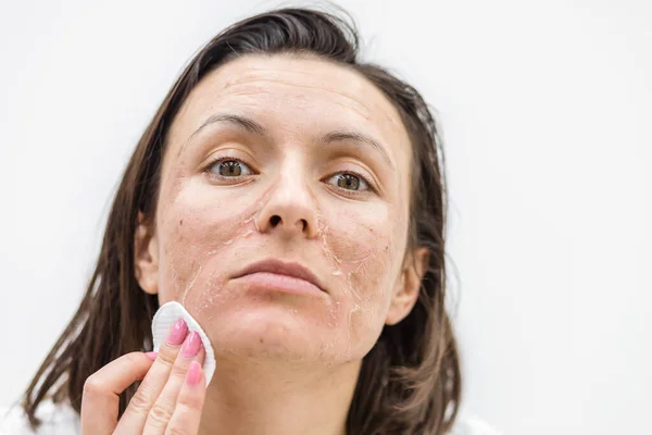 Close up photo of woman cleaning face with cosmetic sponge.