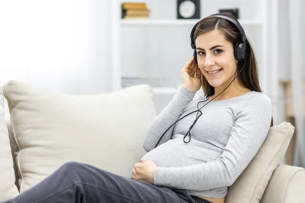 Photo of pregnant woman listening to music on the sofa. — стоковое фото