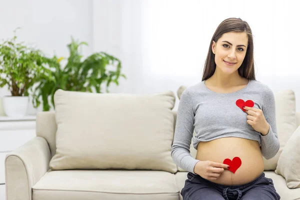 Foto von schwangerer Frau mit rotem Herz in den Händen. — Stockfoto