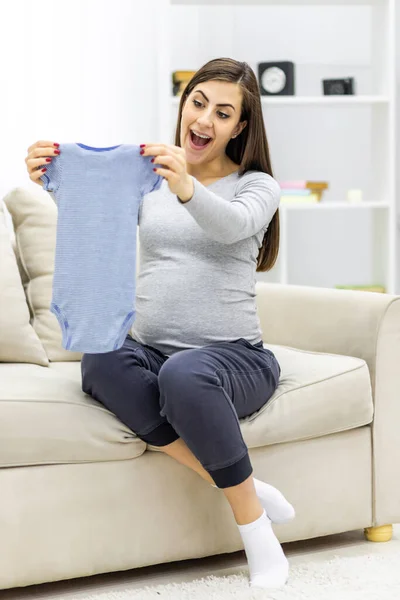 妊娠中の女性の写真子供の小さな服を保持. — ストック写真