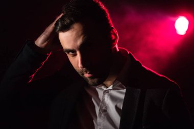 Ayakta duran adamın fotoğrafı ve arka planda pembe ışık..