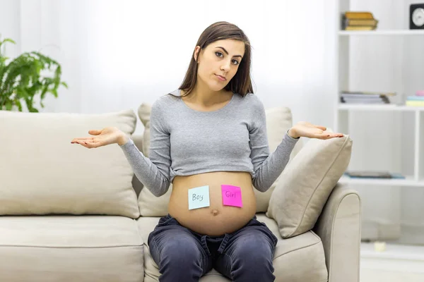 Photo of positive pregnant woman with pink and blue papers on the stomach which mean gender of future baby. — Photo