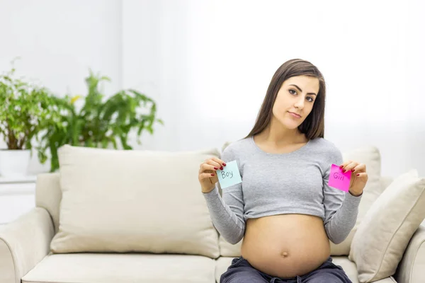 Foto einer positiven schwangeren Frau mit rosa und blauen Papieren, die das Geschlecht des zukünftigen Babys bedeuten. — Stockfoto