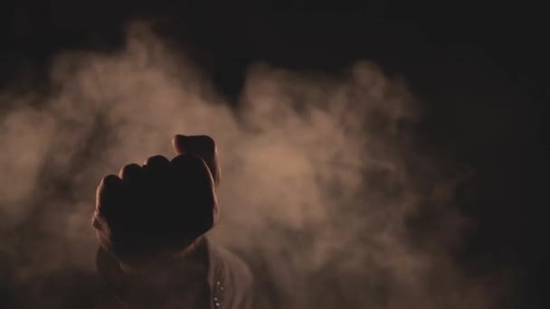 4k slow motion video of male fist in smoke on dark background. — Stockvideo