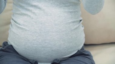 4k, hamile bir kadının elinde pembe ve mavi kağıtlar tutarken ki bu da gelecekteki bebeğin cinsiyeti anlamına geliyor.