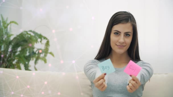 4k slow motion video of pregnant woman holding pink and blue papers which mean gender of future baby. — Video