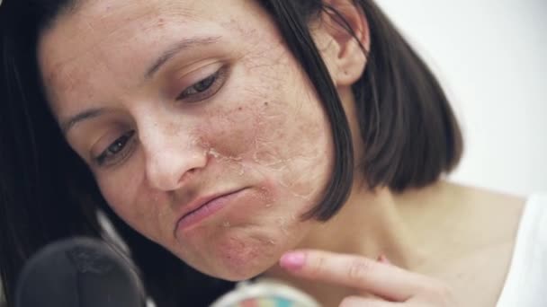 4k крупным планом видео женщины, отслаивающей сухую кожу и смотрящей в зеркало. — стоковое видео