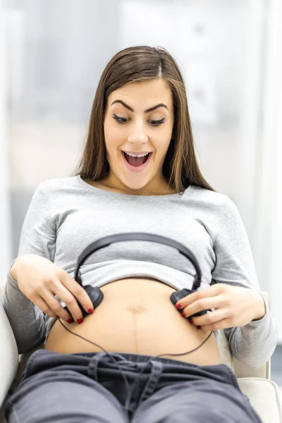 Foto einer glücklichen Schwangeren mit Kopfhörern. — Stockfoto