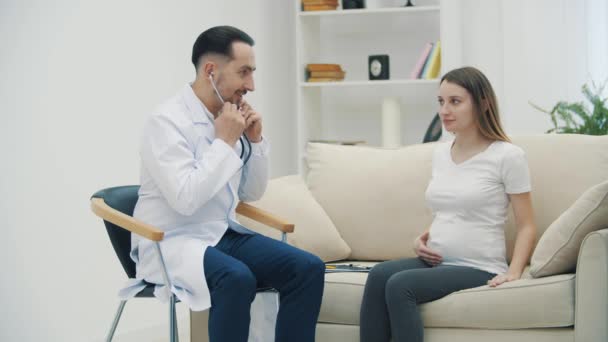 4k slow motion video of doctor examining pregnant woman with stethoscope. — Stockvideo