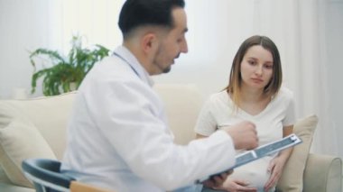 Hamile bir kadının doktorla konuştuğu 4K video. Doktoru ziyaret etme kavramı.