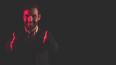 4k video of man in shadow and pink light on the background. Concept of man showing thumbs up.
