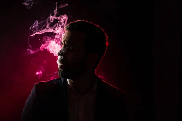 Photo of man smoking in the darkness. Concept of smoking man.