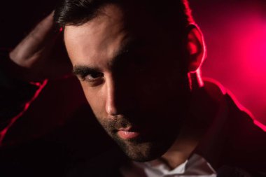 Ayakta duran adamın ve arka plandaki pembe ışığın yakın fotoğrafını çek. Takım elbiseli adam kavramı.