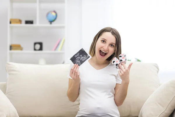 Photo of smiling pregnant woman with ultrasound result. Concept of pregnant woman.