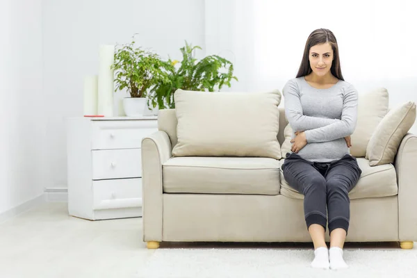 Photo Pregnant Woman Hugging Her Stomach Couch Living Room Concept — Stock fotografie