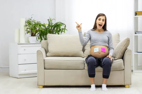 親指を立てて胃の上に青とピンクの紙を持つ妊婦の写真 妊婦の概念 — ストック写真