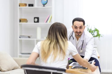 Hamile bir kadının doktorla konuşurken çekilmiş bir fotoğrafı. Sonuçların fotoğrafını izliyor. Doktoru ziyaret etme kavramı.