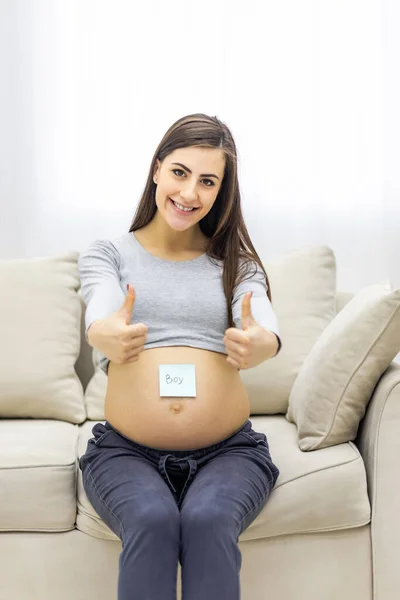 妊娠中の女性が将来の子供の性別を記した紙を持っている写真 妊婦の概念 — ストック写真