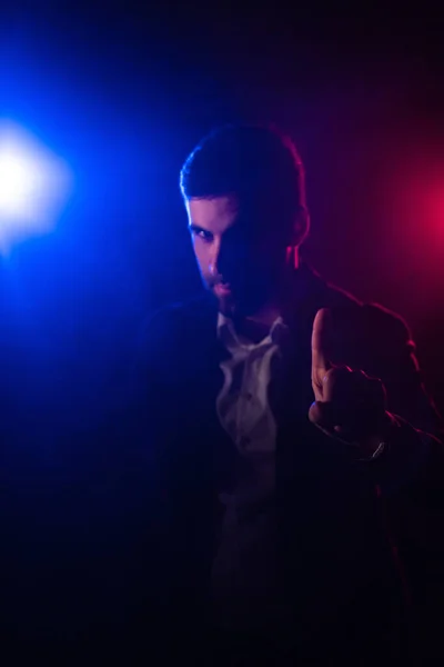 青とピンクのライトで暗い背景にポーズをとる男の写真 拳を示す男の概念 ロイヤリティフリーのストック写真