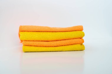 Beyaz arka planda dört sarı-turuncu mikrofiber peçete var. Ev temizleme aracı.