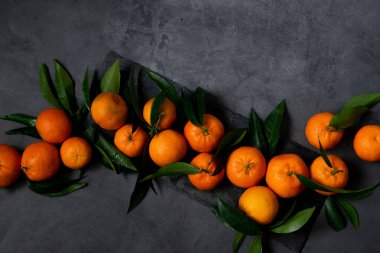 Koyu arkaplanda taze çiğ mandalina, sağlıklı besin maddeleri.