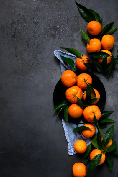 Koyu arkaplanda taze çiğ mandalina, sağlıklı besin maddeleri.