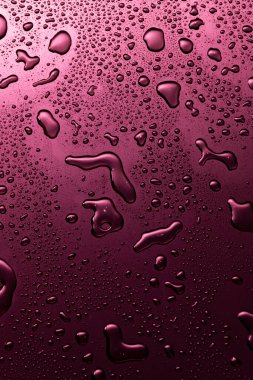 Koyu renk yansıtıcı yüzeyde mor metal su damlaları