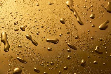Parlak metalik yüzeyde altın metal su damlaları
