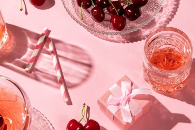 Kirazlar, içkiler ve pembe renkli bir hediye kutusuyla şenlikli bir daire.