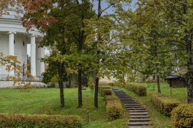 Sonbahar manzarası, eski bir binaya çıkan merdivenler. Düşen yapraklar, renkli ağaçlar. Yatay çerçeve.