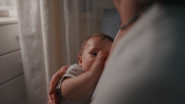 Jeune belle mère, allaitant son nouveau-né le soir, lumière tamisée. Maman allaitement bébé — Video