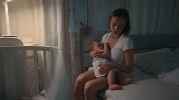 Young beautiful mother, breastfeeding her newborn baby boy at night, dim light. Mom breastfeeding infant — Stock Video