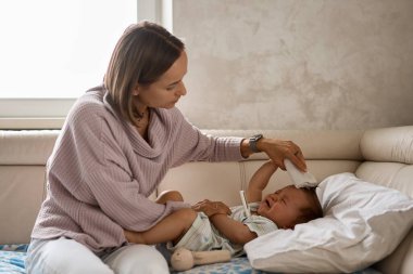 Küçük çocuk yüksek sıcaklıktan dolayı ağlar. Yaşamın ilk yılı. Evde yüksek ateşi olan hasta bir çocuk var.