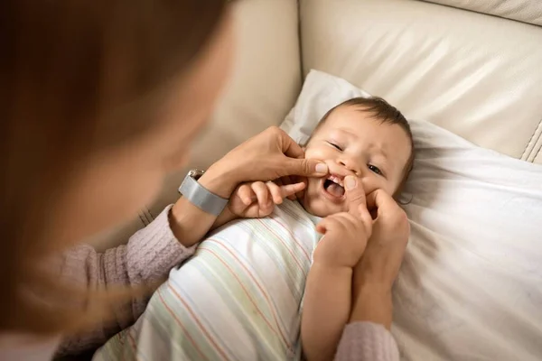 Bayi laki-laki lucu yang ceria berbaring di sofa sementara ibu melihat gigi pertamanya. — Stok Foto