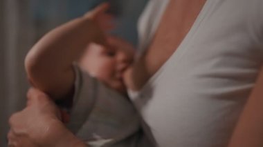 Genç güzel annem, emzirme gece, onun yeni doğan bebek çocuk loş ışık. Anne emzirme bebek