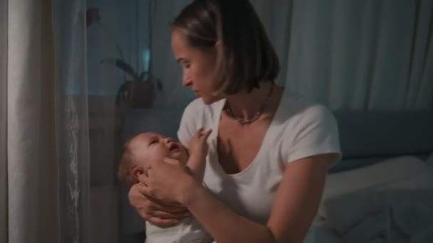 Madre sosteniendo al bebé suavemente calmando al bebé calmando a su madre recién nacida cuidando al niño por la noche — Vídeo de stock