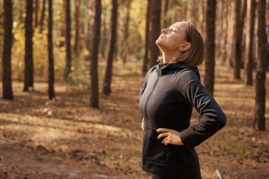 Genç bir kadın gün doğumunda yoga pozisyonu alıyor. Sonbahar ormanında 