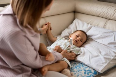 Annesi hasta çocuğunu arka plan, sıcaklığı ölçme. Yüksek ateşle evde kanepe yalan hasta çocuk.
