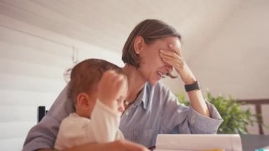 Genç bir anne bebeğiyle ilgilenirken evde bilgisayar kullanarak çalışıyor. Kilitleme sırasında evden çalış