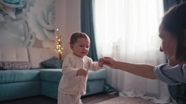 Beyaz bir çocuğun yürümeyi öğrenmesi için ağır çekimde annesine doğru ilk adımı atması. Beyaz bir erkek bebek yerde çıplak ayakla yürüyor. Yüksek kalite 4k görüntü
