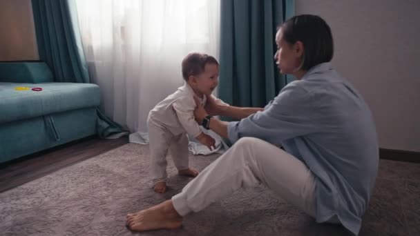 素敵な白人の赤ん坊の男の子のスローモーションは、自宅で母親に最初の一歩を踏み出す歩くことを学ぶ。裸足で床を歩く白人の赤ん坊。高品質4k映像 — ストック動画