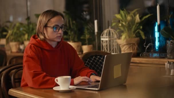 Kafe 'de dizüstü bilgisayarda çalışan beyaz bir kadın ya da blogcu. Teknoloji kullanan üniversite öğrencisi, çevrimiçi eğitim, serbest çalışma. — Stok video