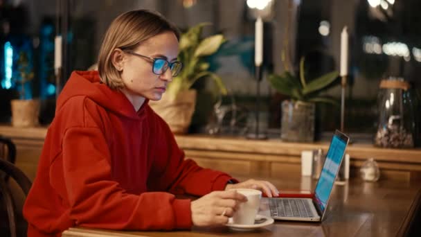 Young Caucasian woman freelancer or blogger working on laptop in cafe. College student using technology , online education, freelance. — Stock Video