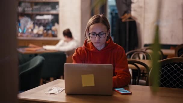 Jonge blanke vrouw freelancer of blogger die werkt op laptop in cafe. College student met behulp van technologie, online onderwijs, freelance. — Stockvideo