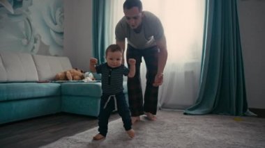 Bebeğin babasıyla ilk adımı atması evde işe yarıyor. Baba, oğlunu ilk adımı atması için cesaretlendiriyor.