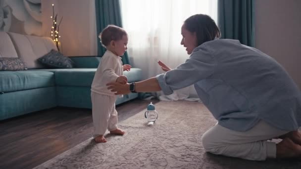 Slow motion van mooie Kaukasische baby jongen leren lopen het nemen van de eerste stap lopen naar zijn moeder thuis. Blanke kleine jongen die met blote voeten op de vloer loopt. Hoge kwaliteit 4k beeldmateriaal — Stockvideo