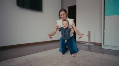 Yakışıklı, gülümseyen çocuk yürümeyi öğreniyor. İlk Bebek Adımları. Bebek ilk adımlarını atıyor.