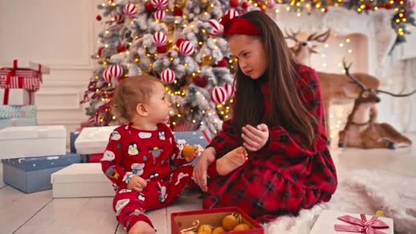 Retrato de vídeo 4k de dos niños pequeños y lindos comiendo dulces de Navidad. Bebé niño prueba dulces caseros. Hermano comiendo dulces cerca del árbol de Navidad — Vídeo de stock