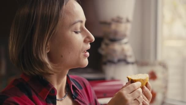 Молодая женщина испытывает свежий кето-хлеб. Крупный план замедленной съемки. Женщина кусает домашний хлеб. — стоковое видео